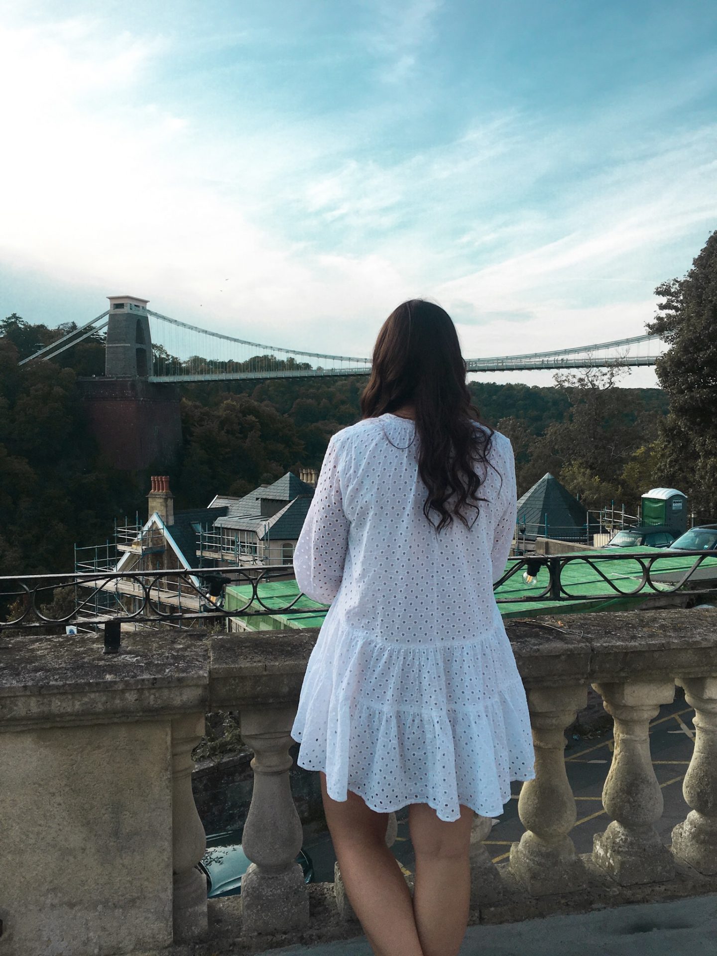 Girl in white dress looking at Bristol clifton suspension bridge